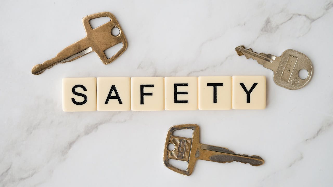 Close-up image of keys and scrabble tiles spelling safety on a marble surface.